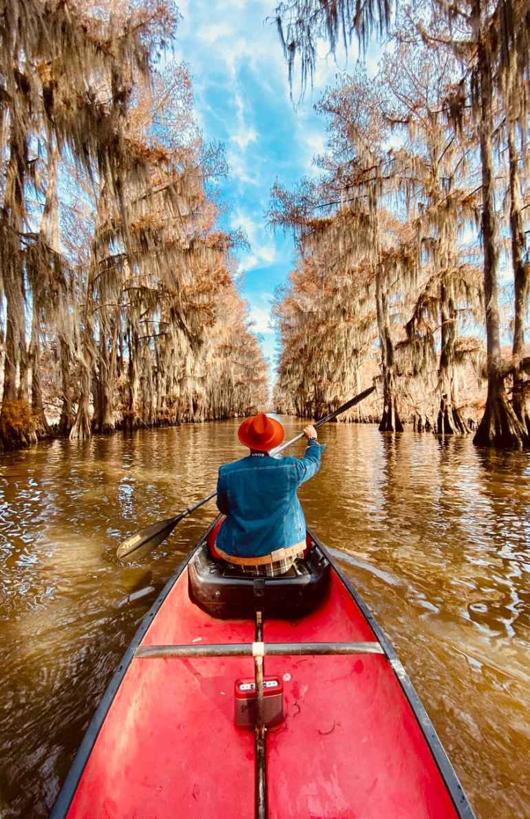 person wearing blue denim jacket riding red canoe boat